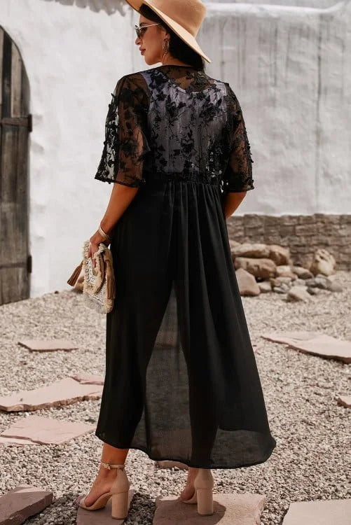 Woman wearing a black lace top and wide-leg pants with a beige hat, standing on a stone path.