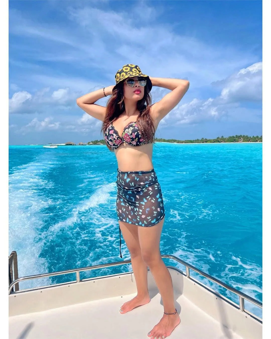 Woman in a bikini and hat on a boat with blue water and sky in the background