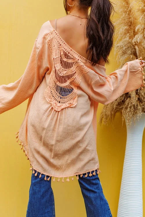 Woman wearing a peach-colored open-back top with blue jeans against a yellow background